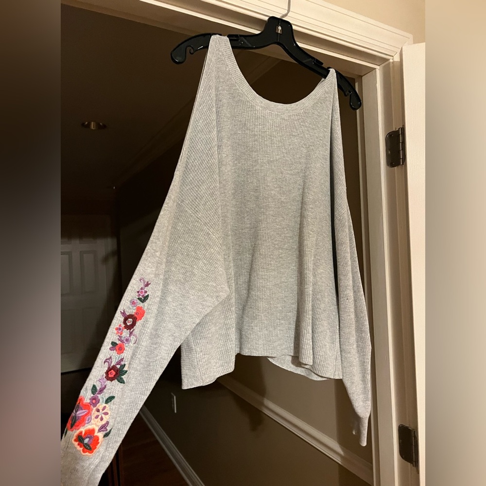 Open shoulder sweater with flowers stitched on the arm